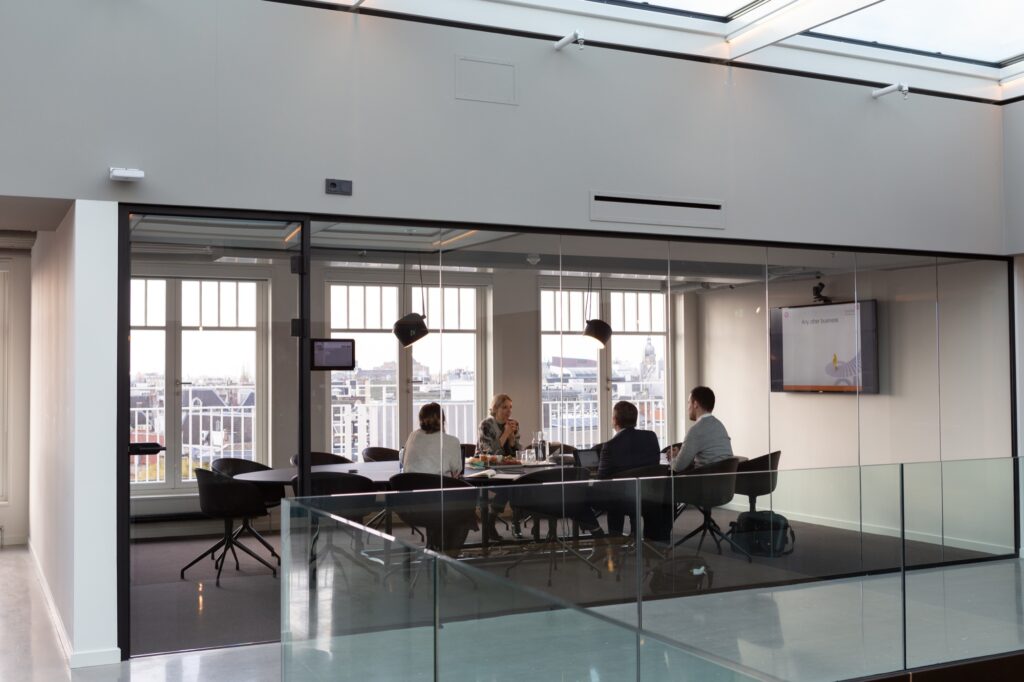 Group of people talking around conference table in glass room